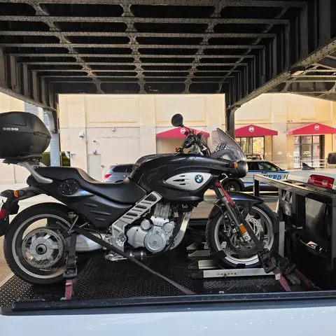 BMW motorcycle with a top case strapped down on the carrier under an elevated city structure