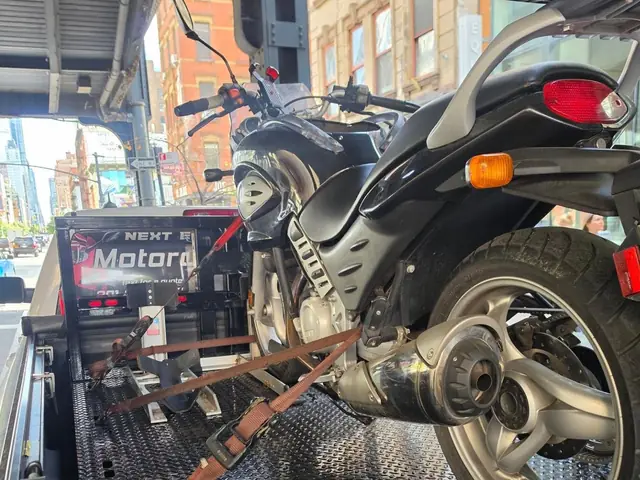 Rear view of a BMW motorcycle strapped down on the carrier behind the truck