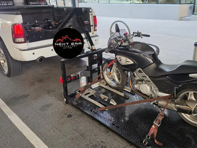 BMW motorcycle loaded on the carrier behind the Next Era Transport truck on a city street