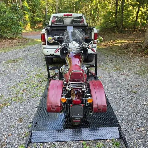 Rear view of a red Moto Guzzi loaded on the carrier behind the Next Era Transport pickup truck