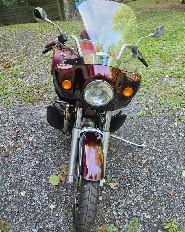 Front view of a red Moto Guzzi with its windscreen, strapped down on the carrier