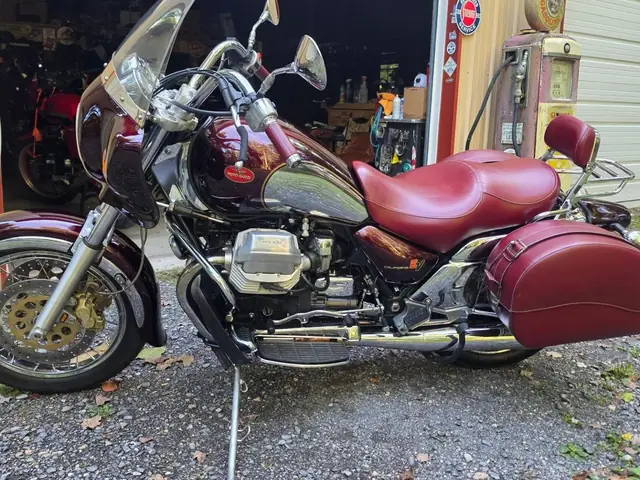Red Moto Guzzi touring bike with hard bags parked on its stand, ready for pickup