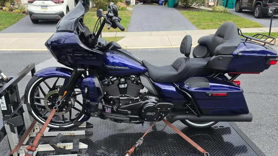 Blue Harley-Davidson Road Glide strapped down on the Next Era Transport carrier deck in a residential street